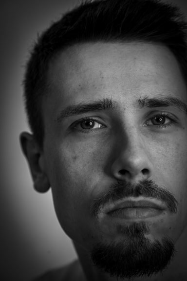 Ein mannlicher Porträt mit ernstem Gesichtsausdruck in Schwarz-Weiß.