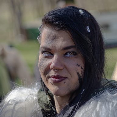 Frau mit schwarzem Haar, schmutzigem Gesicht und einem Pelzkragen.