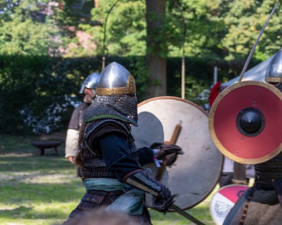 Mittelalterliche Krieger in Rüstung mit Schilden in einem Waldgebiet.