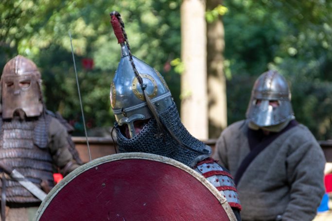 Mittelalterliche Krieger mit Rüstungen und Schilden in einem Waldgebiet.
