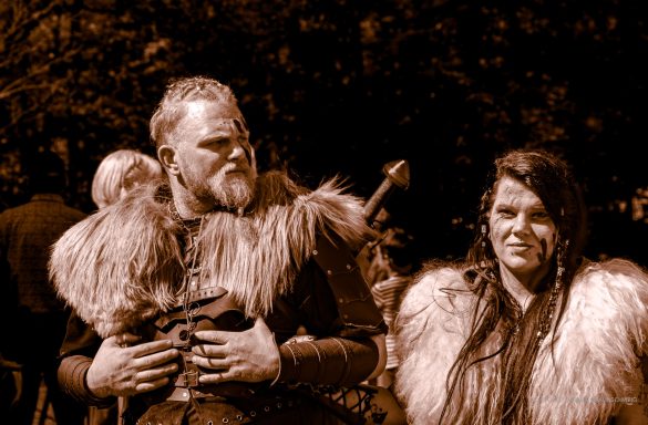 Zwei Personen in historischer Kleidung mit Pelzkragen, umgeben von Natur.