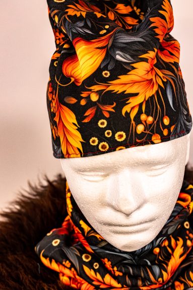 Kopfmodell mit buntem, floralem Schal und Mütze in Orange- und Schwarztönen.