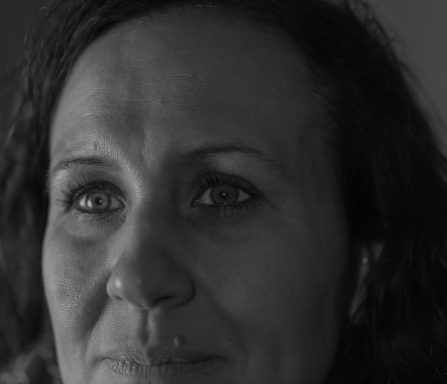 Porträt einer Frau mit lockigem Haar und intensiven, ausdrucksvollen Augen.
