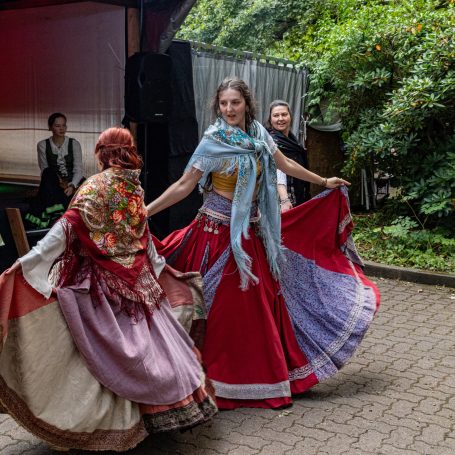 Tanzende Frauen in traditionellen Kleidern bei einer Outdoor-Veranstaltung.