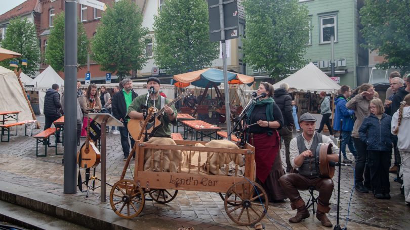Markt mit historischen Ständen und Menschen in mittelalterlicher Kleidung.