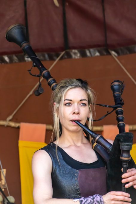 Frau spielt Dudelsack mit einem konzentrierten Ausdruck auf der Bühne.