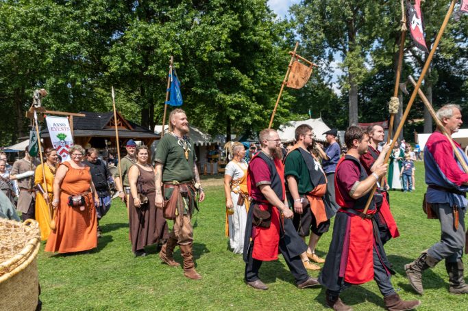 Historische Festzug mit Personen in Mittelalterkleidung und Fahnen im Freien.