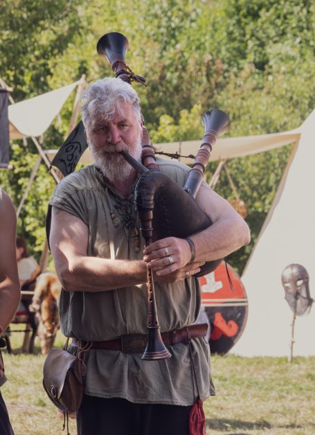 Mann in historischer Kleidung, der traditionelle Blasinstrumente spielt.