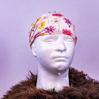 Kopfbedeckung mit bunten Blumenmotiven auf einem weißen Kunstkopf.