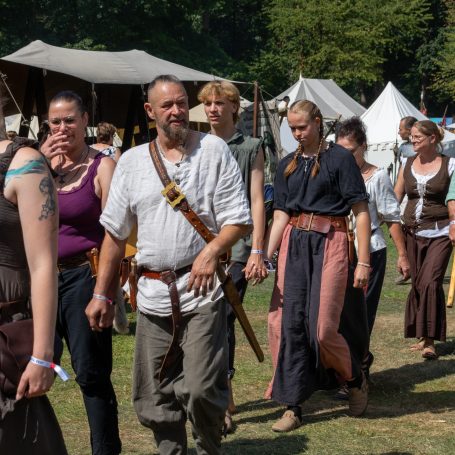 Menschen in historischer Kleidung bei einem Mittelalterfest, in einer grünen Wiese.
