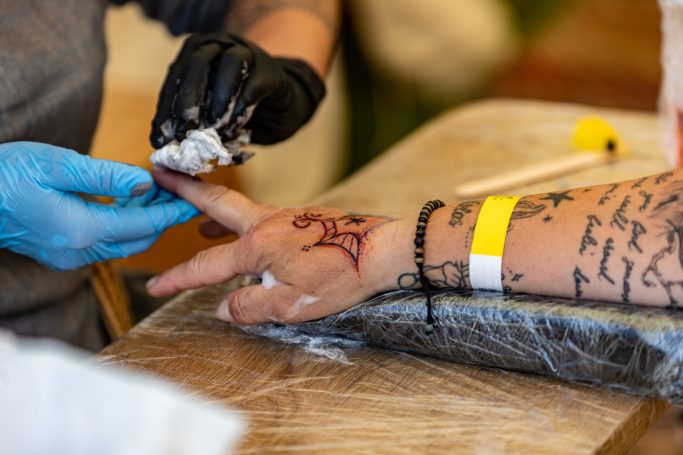 Tattoo wird auf den Finger einer Person mit einem tribalartigen Design aufgetragen.