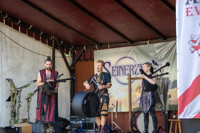 Musiker spielen auf einer Bühne traditionelle Instrumente und unterhalten das Publikum.