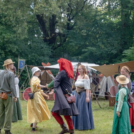 Ein mittelalterliches Fest mit mehreren Personen in historischer Kleidung im Freien.