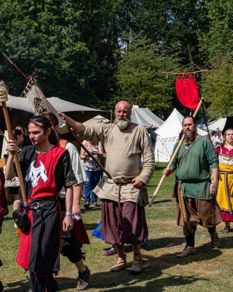 Ritter in historischer Kleidung beim Festumzug in einem grünen Garten.