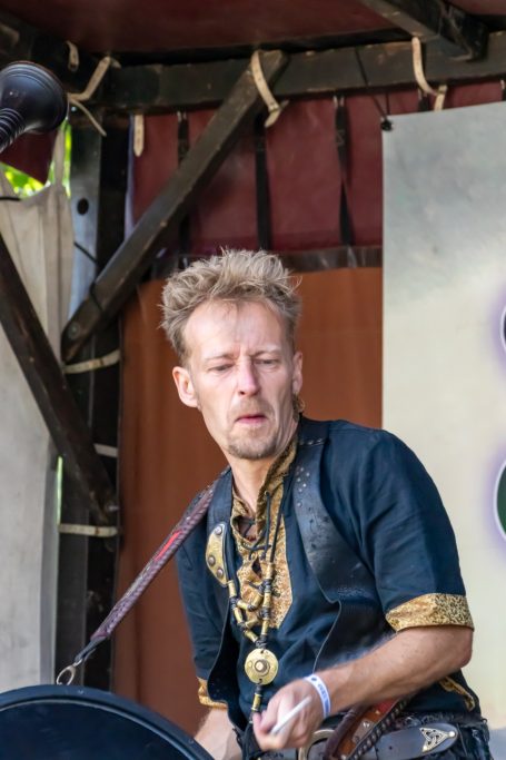 Mann in traditioneller Kleidung spielt Instrument auf einer Bühne.