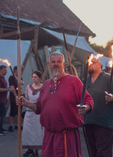 Männer und Frauen in historischen Kostümen mit Fackeln bei einem Festumzug.