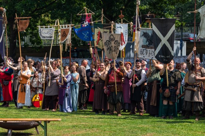 Eine Gruppe von Menschen in historischen Kostümen hält Fahnen und steht im Freien.
