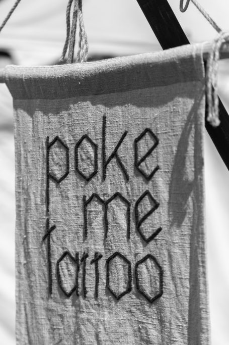 Ein graues Tuch mit dem Schriftzug "poke me tattoo" in schwarz.