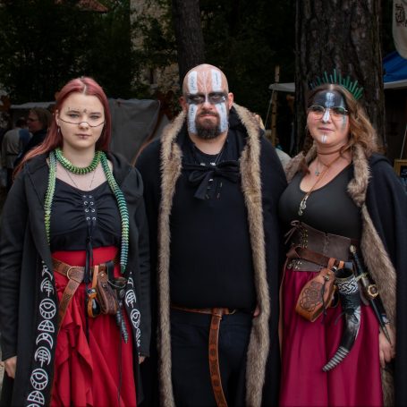 Drei Personen in mittelalterlicher Kleidung mit Accessoires im Freien.