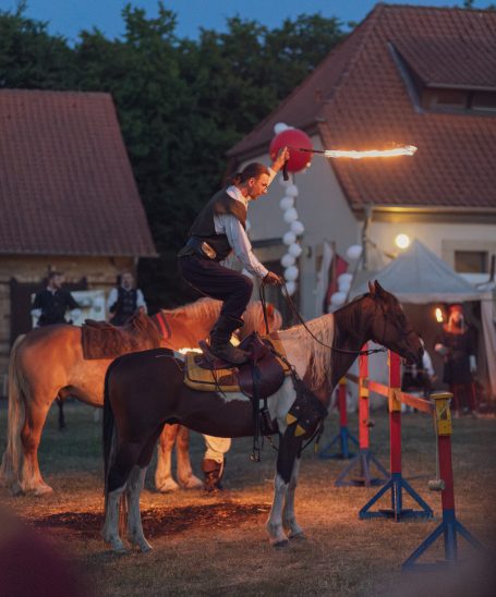 Reiter zeigt Geschicklichkeit auf einem Pferd, während er eine Fackel hält.