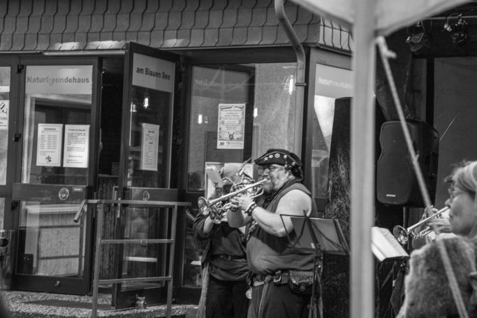 Zwei Musiker spielen Instrumente auf einer belebten Straße in Schwarz-Weiß.