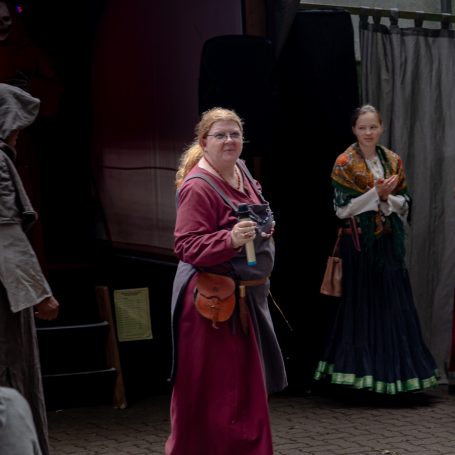 Drei Personen in historischer Kleidung stehen nebeneinander auf einer Bühne.