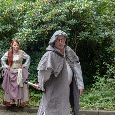 Zwei Darsteller in mittelalterlichen Kostümen, umgeben von grüner Natur.