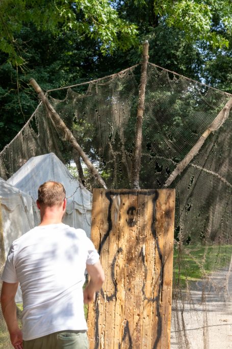 Mann nähert sich einer rustikalen, holzverkleideten Struktur im Freien.