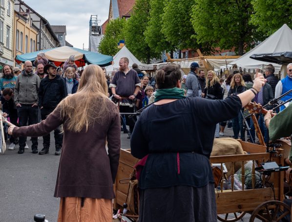 Zwei Frauen stehen mit dem Rücken zu einem lebhaften Markt voller Menschen.