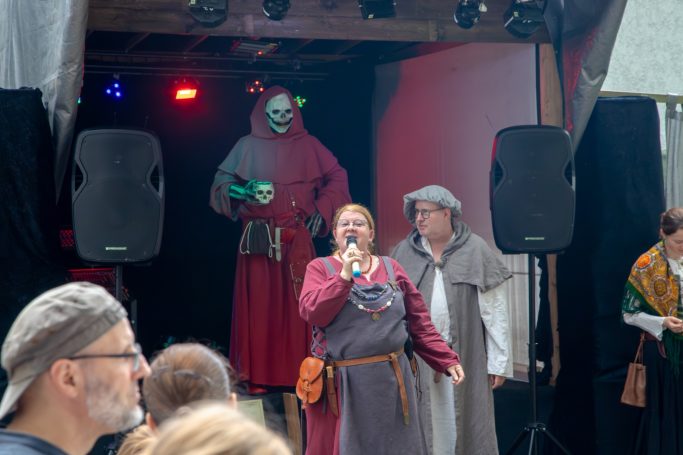 Eine bunte Bühnenszene mit Schauspielern in mittelalterlicher Kleidung und Kostümen.