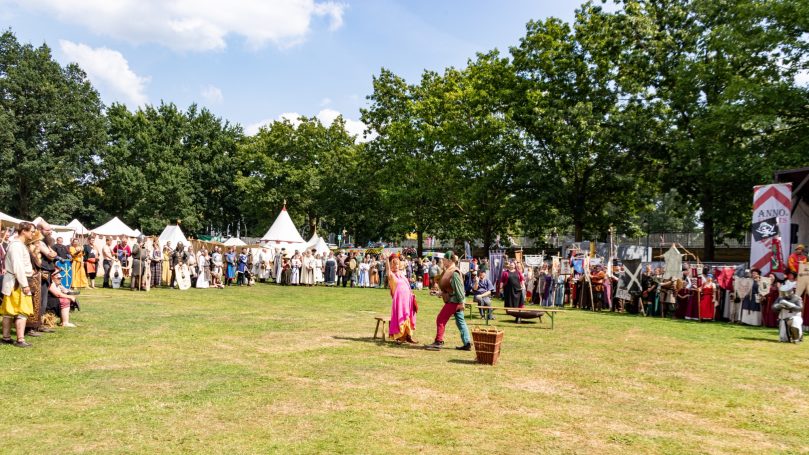 Menschen bei einer Freiluftveranstaltung mit historischen Kostümen und Aktivitäten.