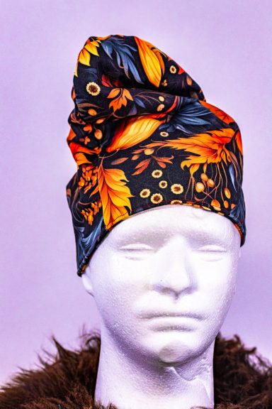 Bunter Hut mit floralem Muster in Orange, Gelb und Schwarz, auf einem weißen Kopfplatz.