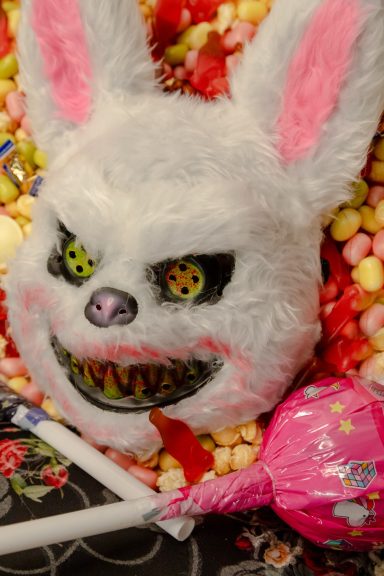 Gruselige Hasenmaske mit furchterregendem Gesicht, umgeben von Süßigkeiten.