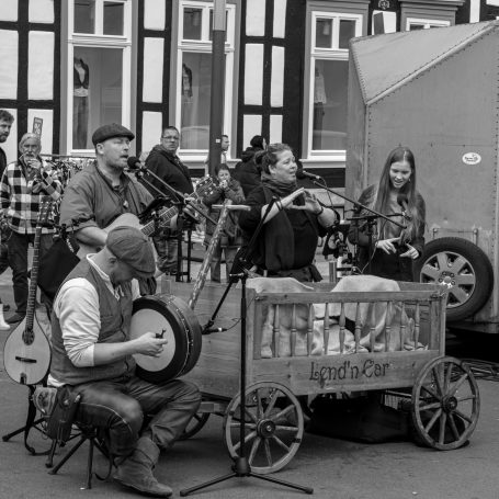 Folkband spielt auf der Straße, Instrumente und Musiker in traditioneller Kleidung.