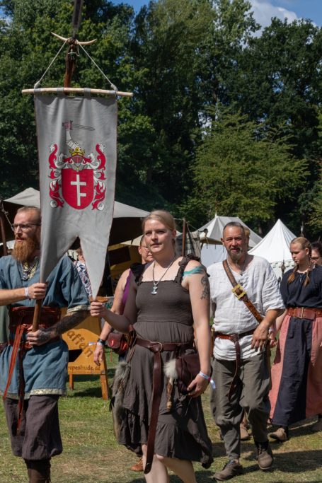 Mittelalterliche Gruppe in historischen Kostümen beim Festumzug mit Fahne.