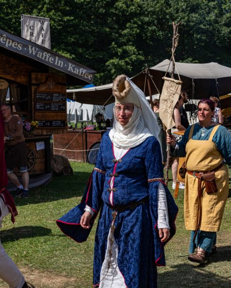 Frau in historischer Kleidung mit Kopfbedeckung auf einem Mittelaltermarkt.